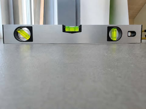 Wasserwaage auf einer frisch ausgeglichenen, ebenen Bodenfläche